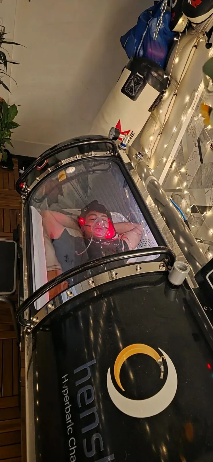 Darren rests inside a clear hyperbaric chamber during an HBOT session