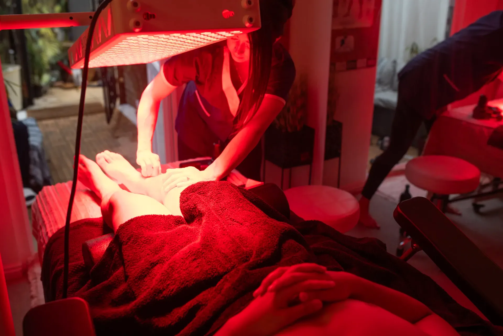 Red-light treatment bed prepared beneath a therapy panel in the treatment room